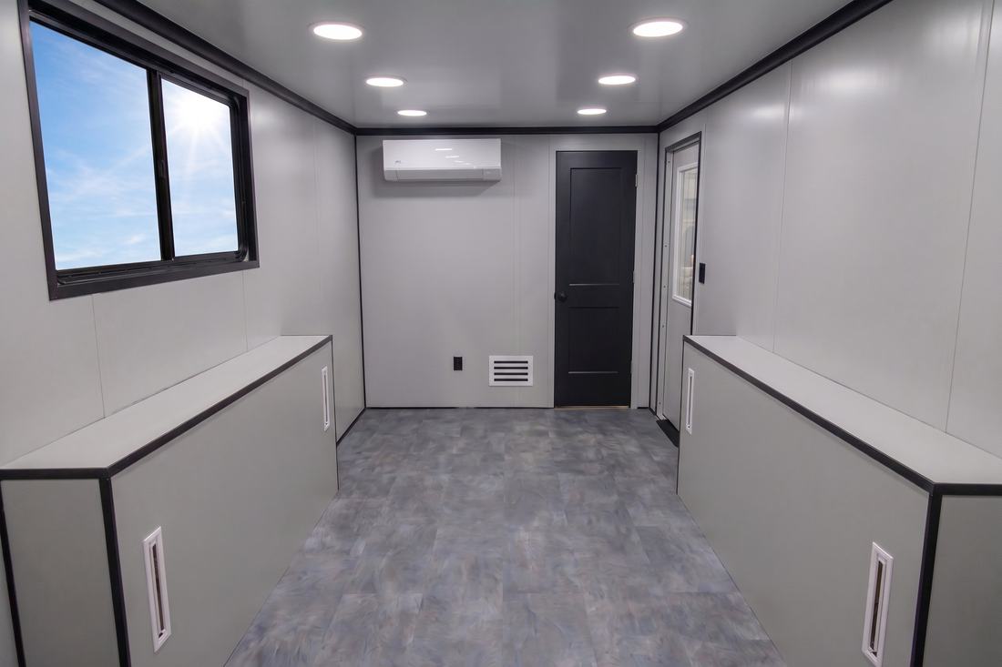 Open interior of a SPOG trailer with counters along both walls, a mini-split heat pump, and a rear door.